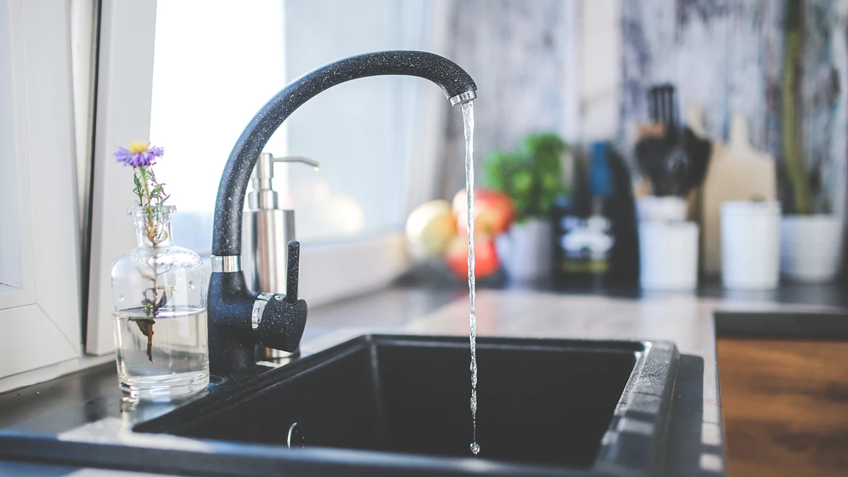 A kitchen sink with a faucet running water, showcasing a clean and functional space for washing dishes or food.