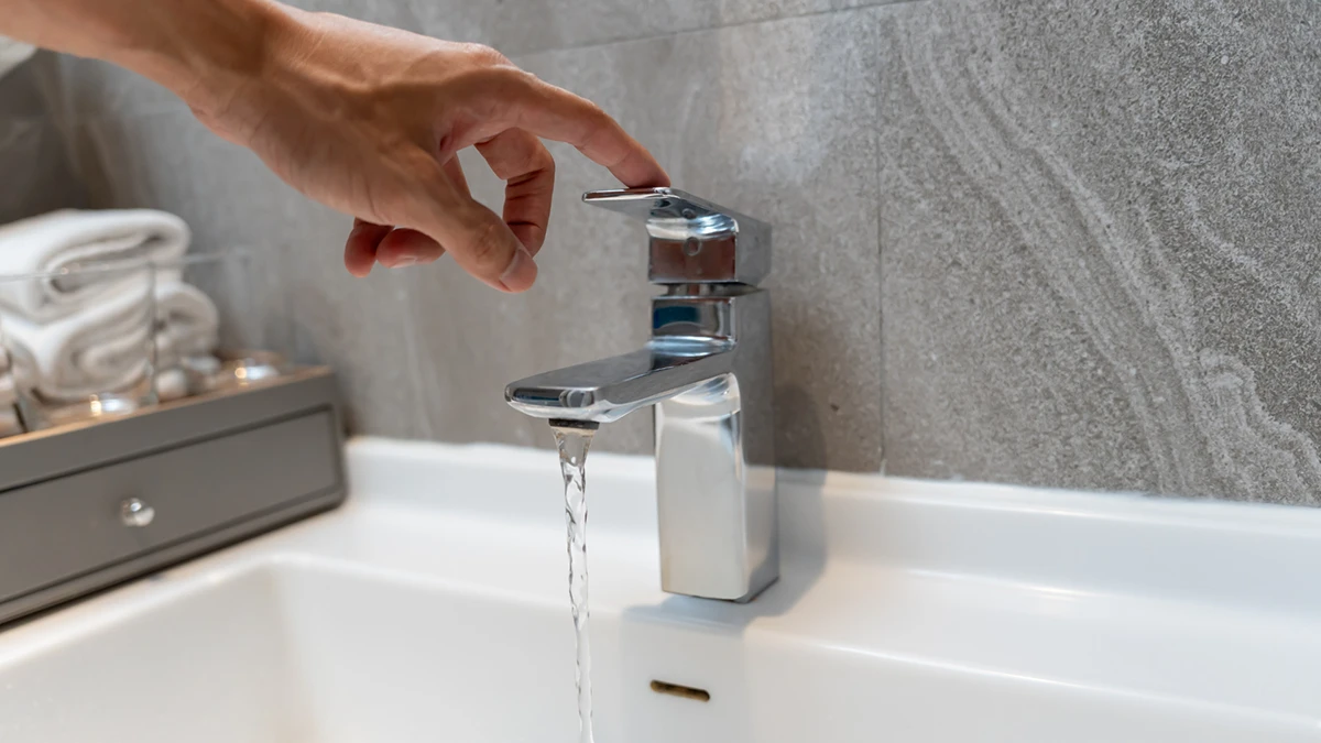 A person is filling a sink with water from a faucet.