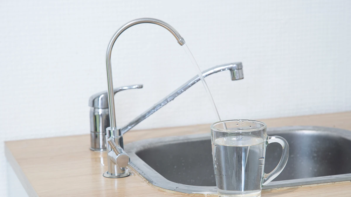 A cup of water placed on a counter beside a sink, reflecting a clean and organized kitchen environment.